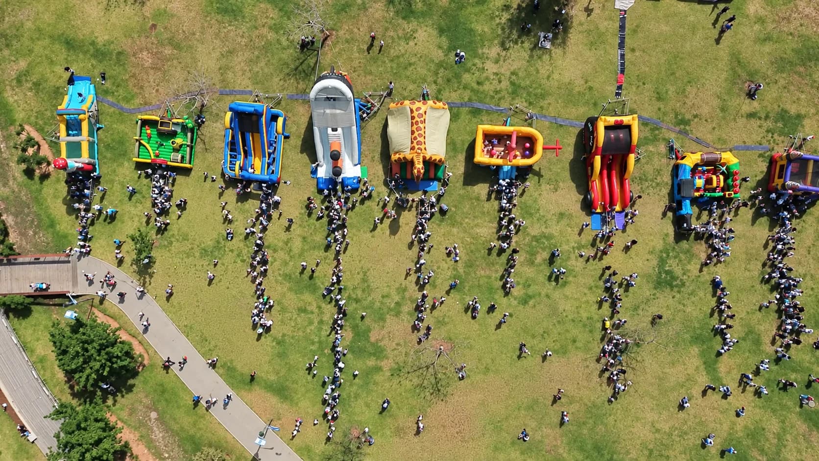 צילום רחפן של מתחם מג׳יקלנד באירוע גני הילדים בהרצליה — שורת מתנפחים צבעוניים ומשתתפים בפארק
